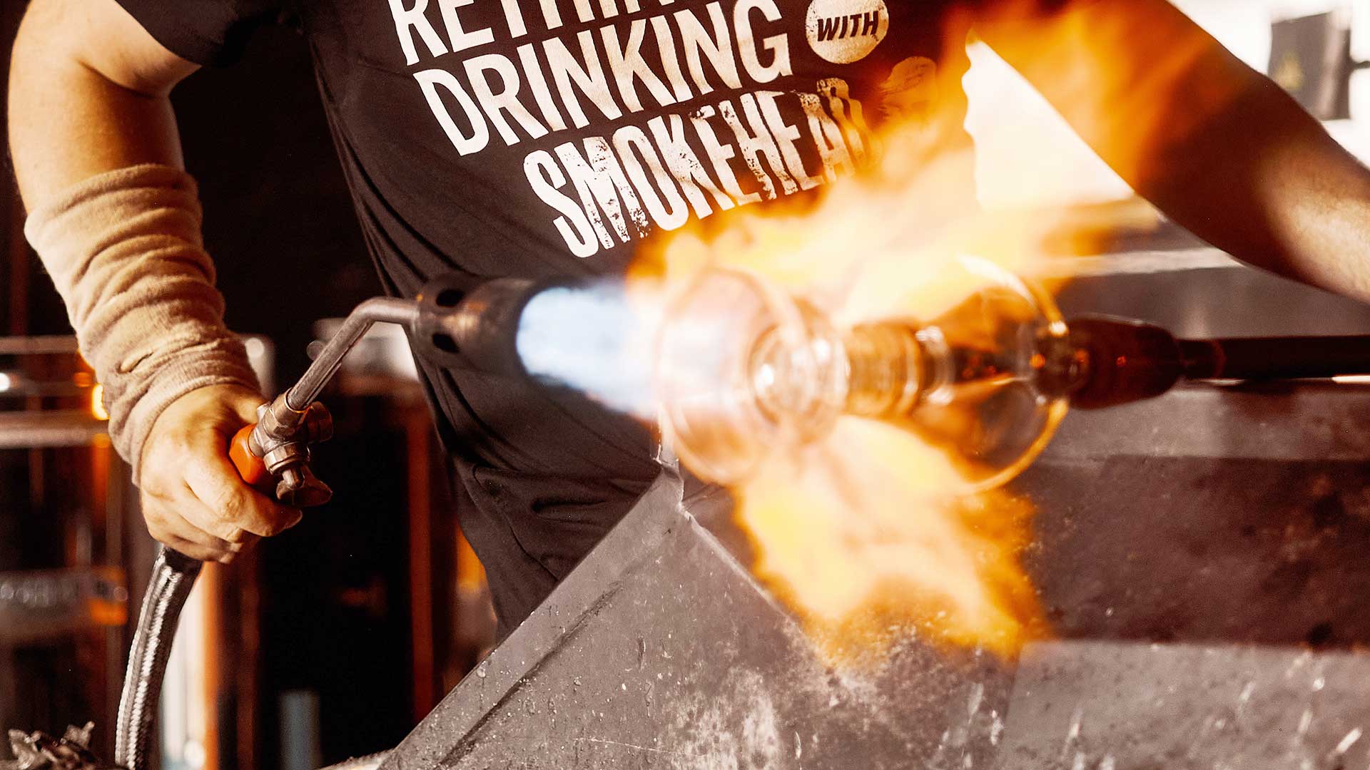 Elliot Walker holding a torch blowing glass.