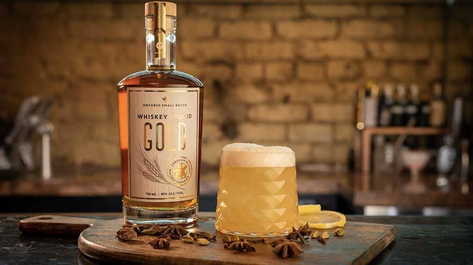 A whisky cocktail on a bar with a bottle of whisky.
