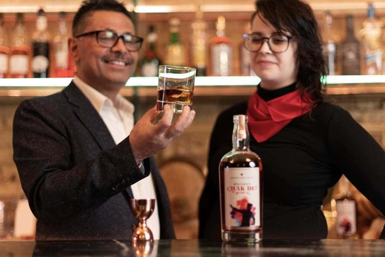 Two people at NB Distillers in Welland, ON, with a bottle of whisky on a bar.