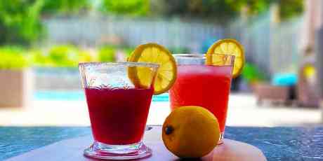 Blackberry Limoncello Martini and Lemonade on a cutting board with a lemon.