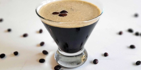 Espresso martini on a counter with espresso beans.