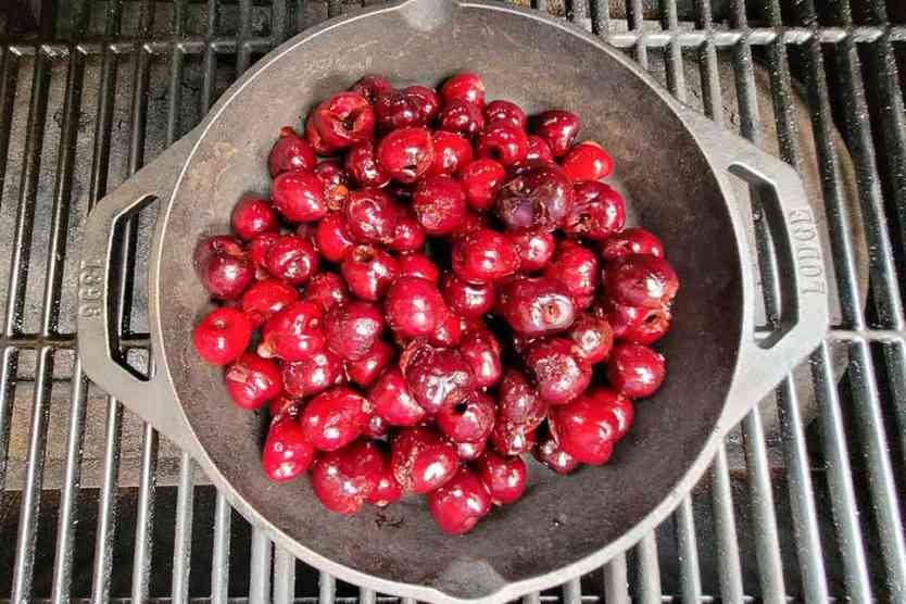 Cherries in a cast iron pan on a smoker.