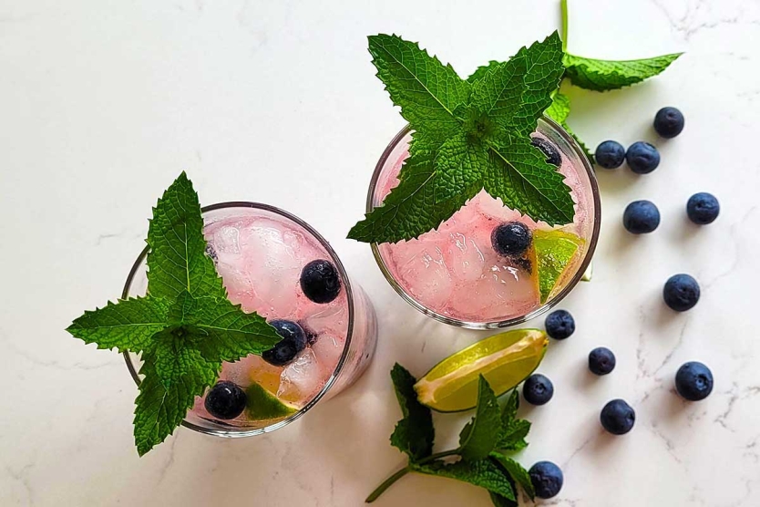 Blueberry mojitos with lime, mint, and fresh blueberries.