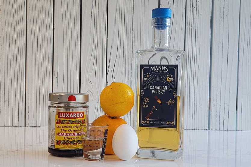 Whisky Sour ingredients including whisky, lemon, orange, egg white, simple syrup, and maraschino cherry.
